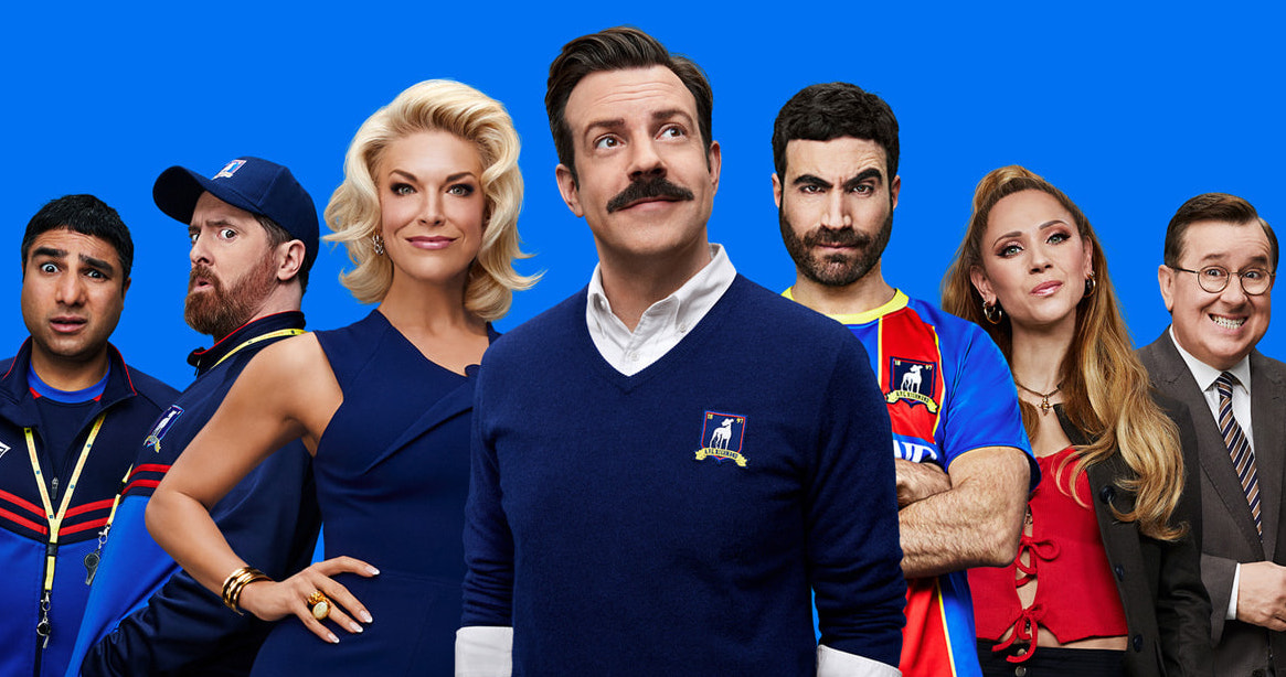 The cast of Ted Lasso against a bright blue background.